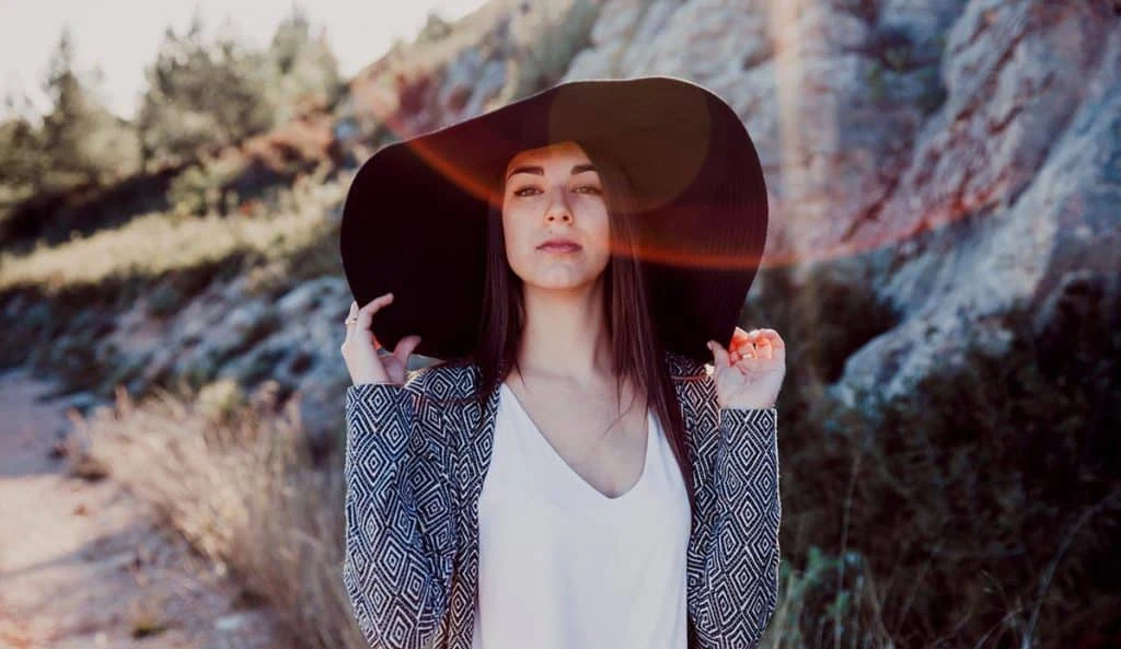 Jeune femme portant un grand chapeau noir en pleine nature